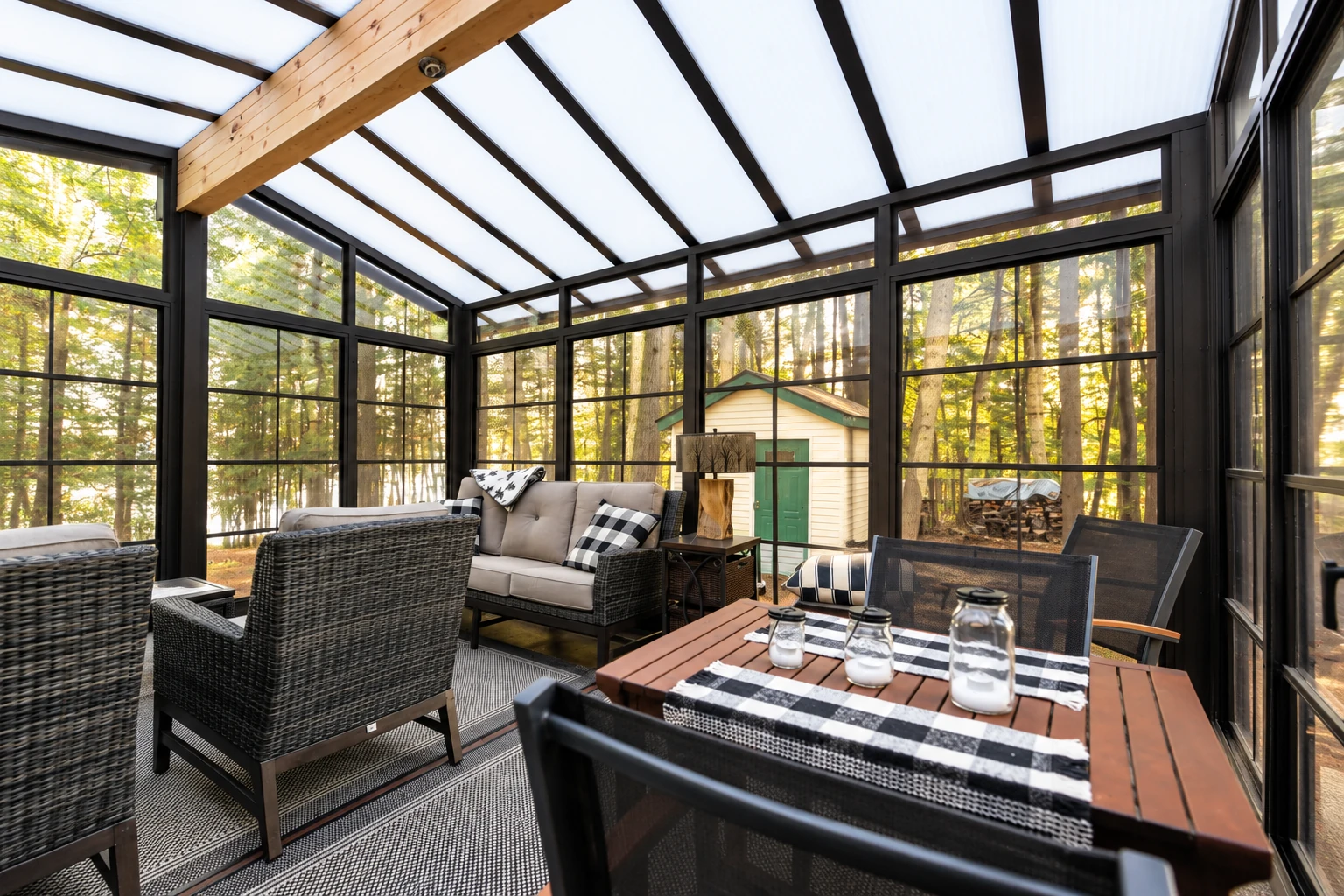 Furnished sunroom with black-framed windows, a translucent sloped roof, wicker seating, and a dining table.